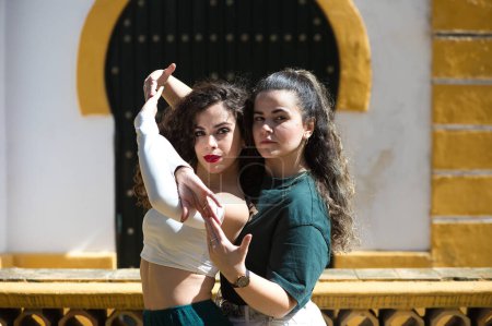 Portrait of a couple of young women dancing to different types of Latin music and dance. The two girls do different postures dancing outdoors in the street. Latin dances and dance concept