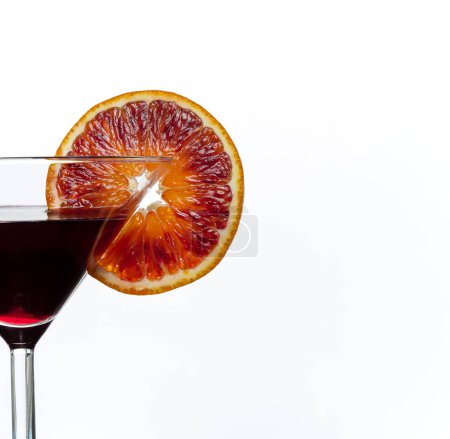 Foto de Bebida morada oscura en copa de cóctel con rebanada de naranja sangre aislada sobre fondo blanco. De cerca.. - Imagen libre de derechos