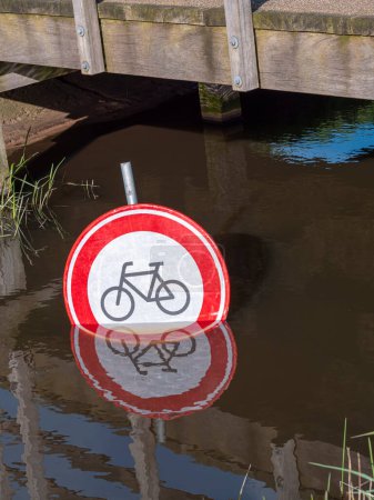Señal prohibida de tráfico de bicicletas bajo un puente en un canal de agua.
