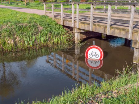 Señal de prohibición para el ciclismo bajo un puente en un canal de agua.