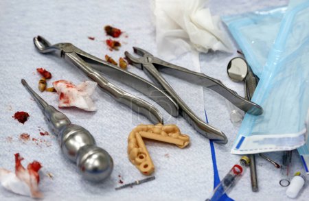 Dental instrument on an operating table post procedure. Dentistry tools, lower premolars forceps dental tool arranged, surgical equipment and stomatology in clinic, dental implant surgery. Teeth model