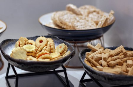 The table with an array of snacks, including bowls of colorful cookies and light, crispy rice cakes. Delicate wafer sticks and crunchy treats added texture to the display, appetizing confectionery.