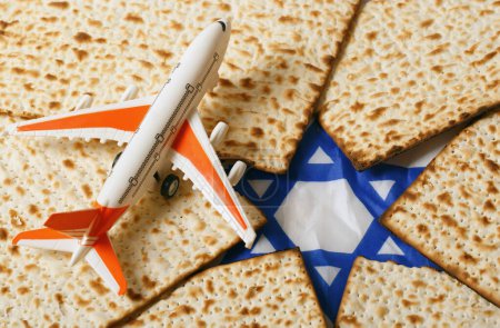 Photo for Airplane with orange wings and a white body, positioned on matzah bread pieces arranged to form a Star of David. This composition symbolizes travel and Jewish Passover celebration. Pesah celebration - Royalty Free Image