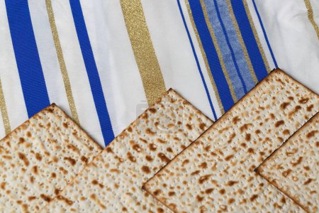 Téléchargez les photos : Matzah, un pain traditionnel sans levain, sur un Tallit, un châle de prière juif avec des rayures dans différentes nuances de bleu, blanc et or. Cette scène est associée à la fête juive de la Pâque - en image libre de droit