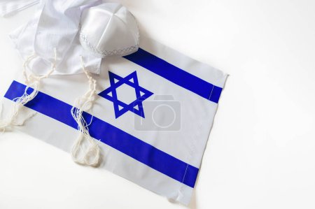 Jüdischer Feiertag zum israelischen Unabhängigkeitstag. Flagge Israels, gekennzeichnet durch blaue Streifen und einen blauen Davidstern auf weißem Hintergrund. Auf der Flagge ruht eine weiße Kippa mit detaillierten Nähten.