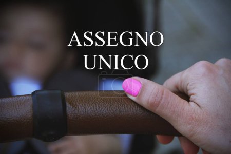 Téléchargez les photos : Près d'une main d'un enfant avec le signe assegno unico concept de chèque de paie du gouvernement italien pour les familles avec enfants - en image libre de droit
