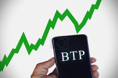 Hand holding a cellphone with the text BTP translating as Italian government bonds