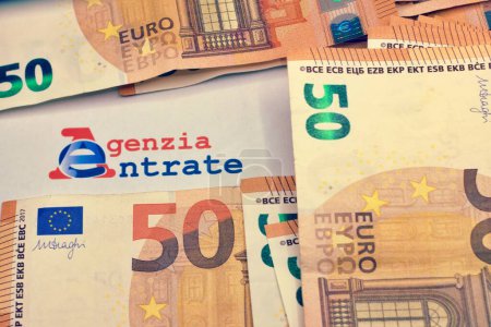Many euro banknotes with the Modello 730 as background , translating in Italian as declaration of incomes , concept of tax payment .
