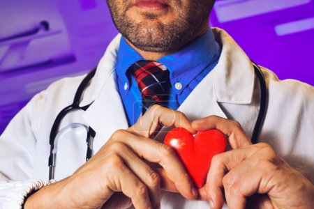 Hands of doctor man holding a red heart, showing symbol of love, human support to patient, promoting medical insurance, early checkup for healthcare, cardiologist help. Close up of object