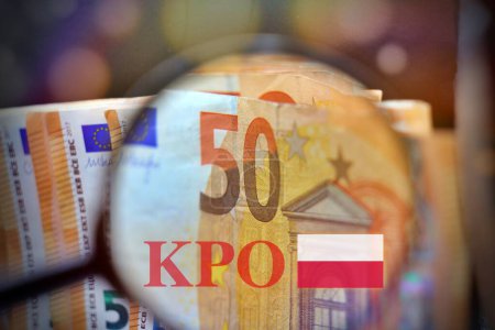Lupe über dem Geldhaufen mit der Aufschrift KPO, die neben Eurogeld Krajowy Plan Odbudowy ist. Neues EU-Programm für Polen