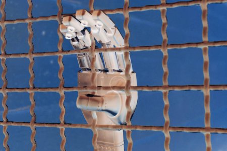 Téléchargez les photos : Main d'un robot dans une cellule de prison avec des barres. - en image libre de droit