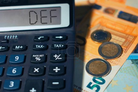Téléchargez les photos : Calculatrice avec billets de banque avec le mot "Def" document de l'économie et des finances du gouvernement. - en image libre de droit
