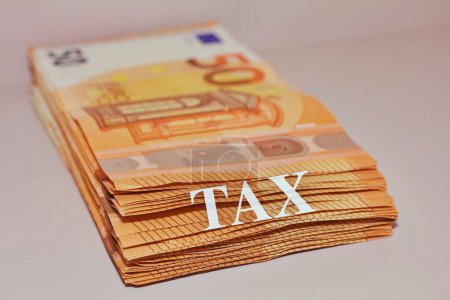 Pila de billetes en euros con el texto "Impuestos" .