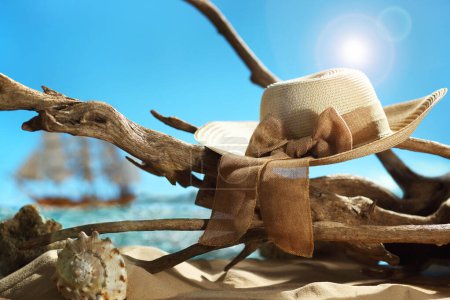 Foto de Sombrero de verano de paja vintage colgando de la parte superior de madera a la deriva en una playa de arena - Imagen libre de derechos
