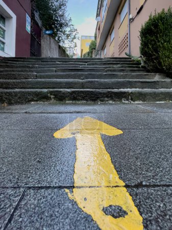 Símbolo tradicional de flecha amarilla en el camino francés de Santiago. Señal de orientación para peregrinos en Sarria. Ruta de peregrinación al apóstol Santiago.