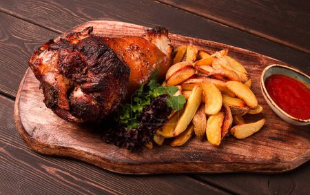 Pork knuckle, in soy-honey sauce, with fried potatoes, on a wooden chopping board, homemade, no people,