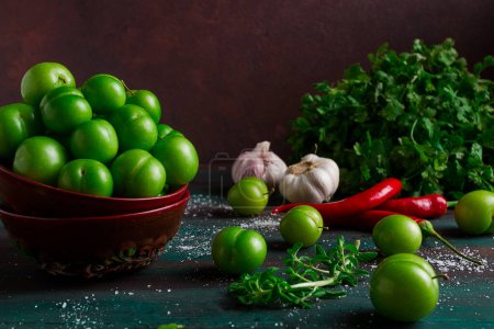 Photo for Tkemali, green cherry plum, with ingredients for sauce, cilantro, mint, hot pepper, garlic, on a wooden table, close-up, rustic, food background, no people, selective focus, - Royalty Free Image