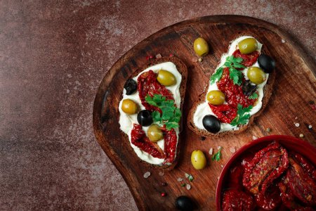 Photo for Sandwich with cream cheese, dried tomatoes, olives, breakfast, top view, - Royalty Free Image