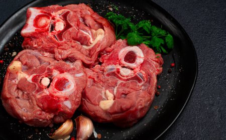 steak cru, cou de veau sur l'os, viande fraîche, sur une assiette noire, vue de dessus, personne,