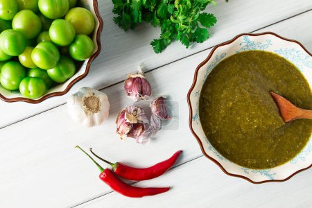 Tkemali sauce, traditional Georgian cuisine, green cherry plum, with ingredients for sauce, cilantro, mint, hot pepper, garlic, on a white wooden table, close-up, rustic, food background, no people, selective focus, sauce, green sauce, tkemali, georg