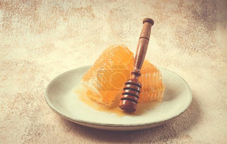 honeycomb, with a wooden spoon-spindle, on a plate, no people,