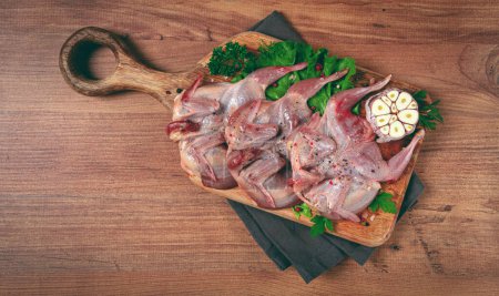 Raw quail meat, on a cutting board, with spices and herbs, top view,