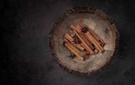 cinnamon sticks, with nutmeg and anise star, in a wooden plate, top view, no people,