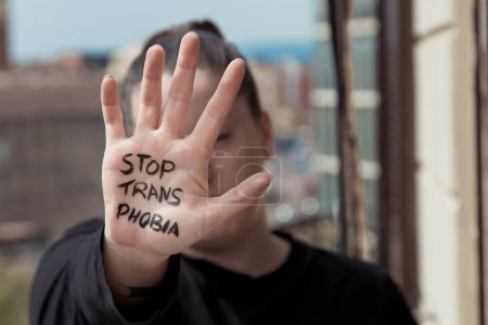 Foto de Chica tiene una mano delante de ella con un mensaje escrito en la palma de su mano para la transfobia - Imagen libre de derechos