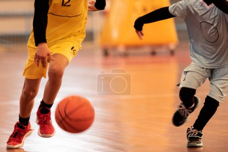 Foto de Unrecognisable boys play basketball in a sports hall game - Imagen libre de derechos