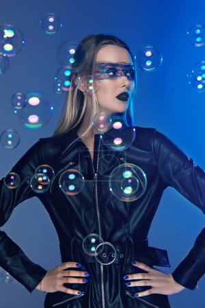 Girl in leather clothes with artistic makeup on a blue backgroun