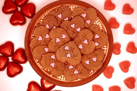 Vegetarian cookies of different types of hearts made using plungers. Decorated with natural juices thickened with agar-agar. Gold background.