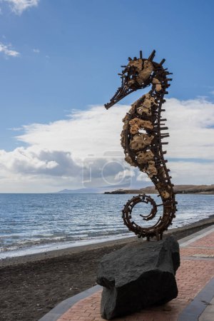 Photo for Metal skelet of a seahorse statue, filled with stones. Atlantic ocean promenade. Blue sky with white clouds in the winter. Tarajalejo, Fuerteventura, Canary Islands, Spain. - Royalty Free Image