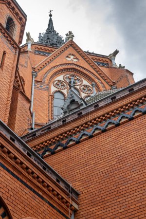 Verzierte Fassade der Kirche der Heimsuchung der Jungfrau Maria. Alle Details aus Ziegelsteinen. Im Hintergrund ein neugotischer Turm mit einem Kreuz auf der Spitze. Postorna, Breclav, Mähren, Tschechische Republik.