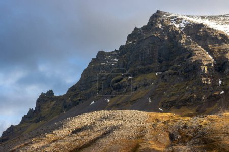 Foto de Alta montaña majestuosa. Vista en el pico con un poquito de primera nieve en otoño. Cielo nublado. Zona de Isafjordur, Westfjords, Islandia. - Imagen libre de derechos