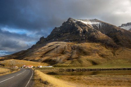 Foto de Majestuosa montaña con un toque de nieve en otoño. Cielo nublado, pero la luz con algunos rayos de sol. Río en el valle. Zona de Sydridalur, Westfjords, Islandia. - Imagen libre de derechos