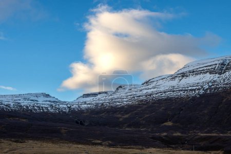 Foto de Inicio del atardecer durante un día con cielo azul y algunas nubes. Majestuosas montañas con poca nieve en otoño. Zona de Westfjords, Isafjordur, Islandia. - Imagen libre de derechos
