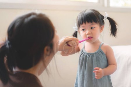 Photo for Asian mother and daughter brushing their teeth together, Mom teaching his daughter how to brush teeth, Oral health concept - Royalty Free Image