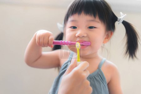 Photo for Asian mother and daughter brushing their teeth together, Mom teaching his daughter how to brush teeth, Oral health concept - Royalty Free Image
