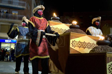 Téléchargez les photos : Ibi, Espagne - 5 janvier 2022. Paje royal en costume coloré aidant les Mages à apporter de l'or, de l'encens et de la myrrhe à l'enfant Jésus, et des jouets aux enfants. Cadeaux et cadeaux. - en image libre de droit