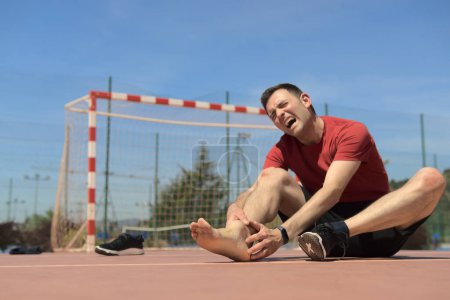 Verstauchtes Sprunggelenk. Verletzung im Futsal-Sport. Männliche Berührung des Fußes unter Schmerzen aufgrund von geschwollenem und gebrochenem Knöchel. Fußballrisiko. Hochwertiges Foto