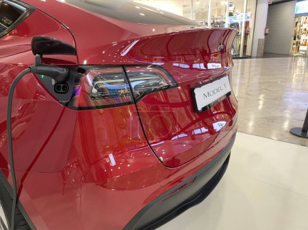 Téléchargez les photos : Gros plan Alicante, Espagne - 5 octobre 2023. Nouveau véhicule électrique Tesla Modèle Y exposé dans un centre commercial. Voiture électrique rouge dans le centre commercial. Photo grand angle horizontale - en image libre de droit