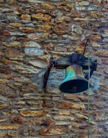 Téléchargez les photos : Cloche en laiton antique suspendue dans un jardin victorien. Cloche en laiton sur un mur de pierre dans le vieux style. - en image libre de droit