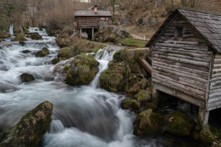 Téléchargez les photos : Rivière de montagne avec des roches moussues et des moulins à eau en bois en exposition longue, rivière Krupa à Krupa na Vrbasu - en image libre de droit