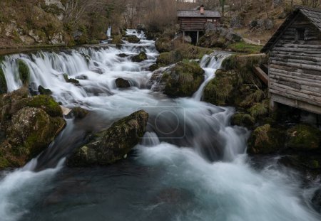 Téléchargez les photos : Rivière de montagne avec des roches moussues et des moulins à eau en bois en exposition longue, rivière Krupa à Krupa na Vrbasu - en image libre de droit