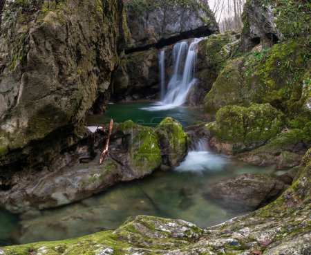 Wasserfall oder Kaskade am Gebirgsbach, felsige Schlucht mit steilen Klippen, nasse Felsen mit Moos bewachsen