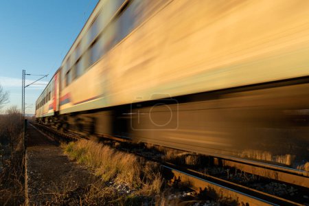 Train passing with motion blur, railroad travel passenger train during sunny day