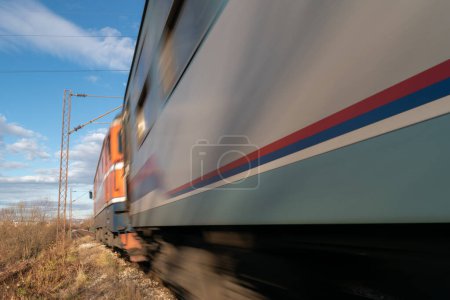 Zug im Vorbeifahren mit Bewegungsunschärfe in der Landschaft von Banja Luka, Nahaufnahme eines Personenzuges