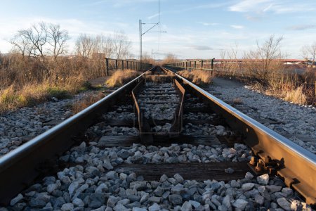 Schienen mit Holzbinder und Oberleitung am sonnigen Abend, Eisenbahnverkehr