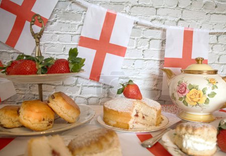 Celebración San Georges día por la tarde té vintage bollos tradicionales fresas y crema victoria esponja pastel bandera de Inglaterra bunting 
