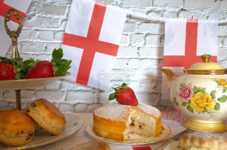 Celebración San Georges día por la tarde té vintage bollos tradicionales fresas y crema victoria esponja pastel bandera de Inglaterra bunting 